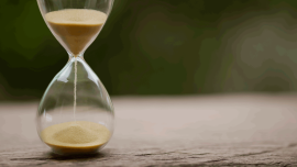 Sand clock , Hourglass as time passing on green nature background - Image credit - iStock- 1342058281