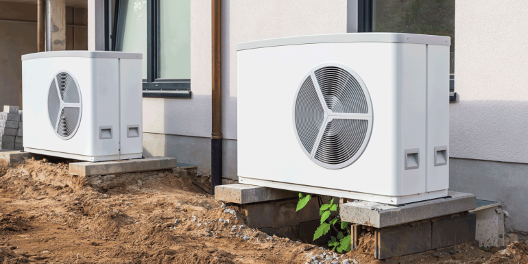 Two air source heat pumps installed outside of new and modern city house under construction-Image credit-Shutterstock-2350417021