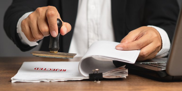 Businessman stamped rejected on a document while sitting in the office