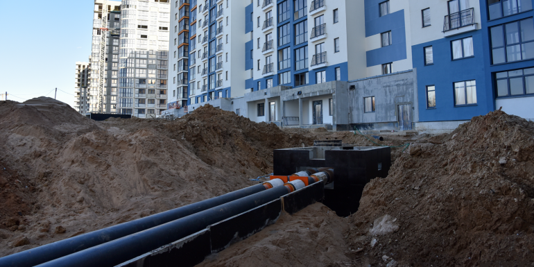 Laying heating pipes in a trench at construction site.CREDIT-shutterstock-1705044463