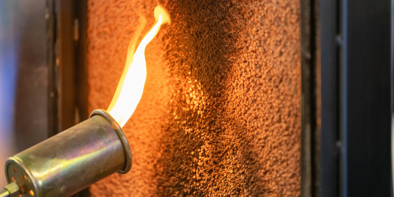 Close up of a flame torch testing flame retardant material, demonstrating fire resistance and safety. shutterstock_2473469235