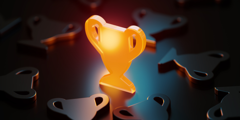 Trophy symbol glowing amid black trophy symbols.credit_istock-1503369669