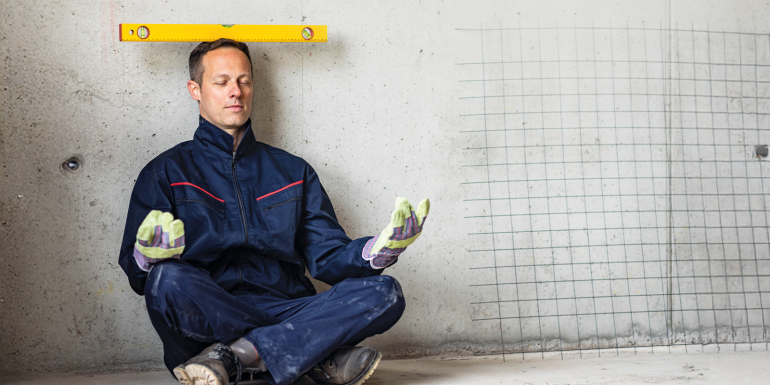 Construction worker meditating with spirit level.