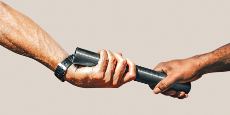 Team mates passing a relay baton.CREDIT_shutterstock_2513730383