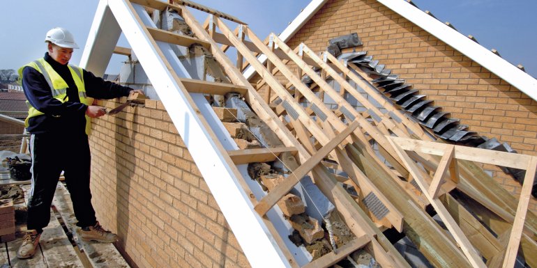 Trainee bricklayer completes a wall on a new housing estate. CREDIT_Alamy_A8HYX0