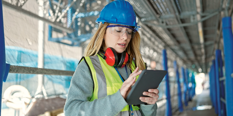 Young blonde woman builder using touchpad at street