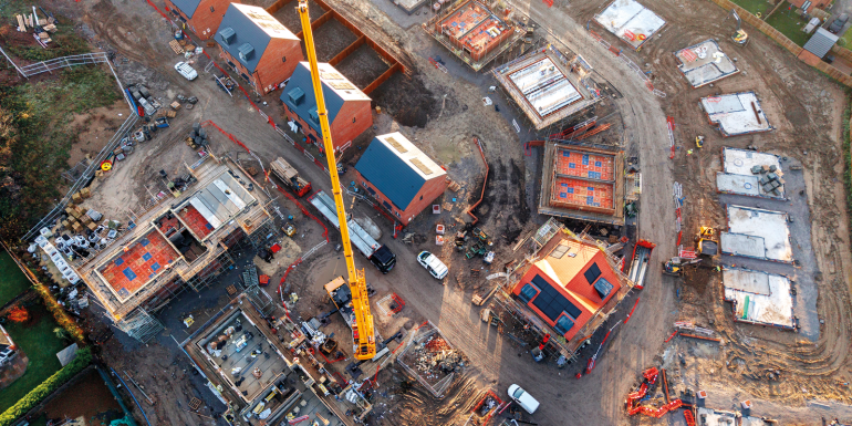 Aerial view of construction workers operating yellow mobile crane at residential building site stock photo