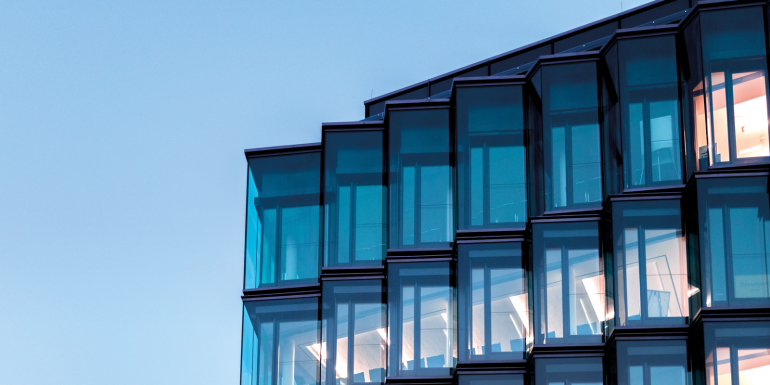 Modern glass facade of new architecture in berlin at blue hour. CREDIT_istock-1290315737