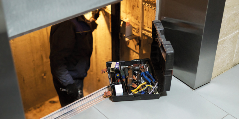 Specialist fixing or adjusting lift mechanism in elevator schaft. Image credit | Alamy