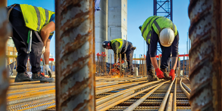Construction workers installing and cutting steel reinforcement for rc concrete slab. Men at work. Leading lines.