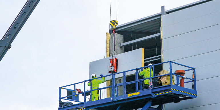 Sandwich panels wall mounting using crane and scissor lift. Image credit | iStock