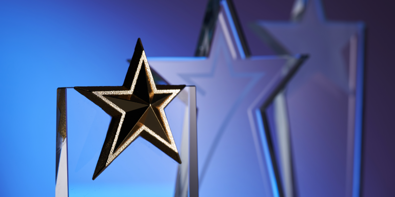 group of star shape crystal trophies against blue and pink background.CREDIT_shutterstock_2215170457
