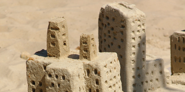 Sand sculptures of miniature city buildings.CREDIT_iStock-518385234