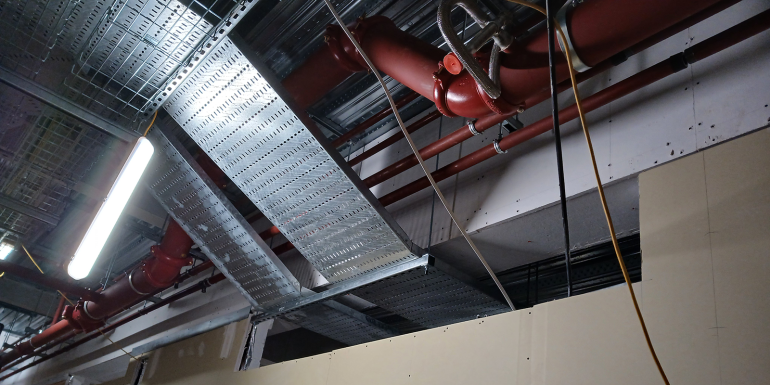 Services have been installed without allowance for fire stopping access and the fire-resisting steel encasement has been installed too close to the cable tray
