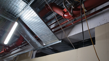 Services have been installed without allowance for fire stopping access and the fire-resisting steel encasement has been installed too close to the cable tray