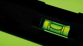 SPIRIT LEVEL TOOL ON GREEN BACKGROUND.Image credit | alamy