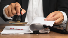 Businessman stamped rejected on a document while sitting in the office