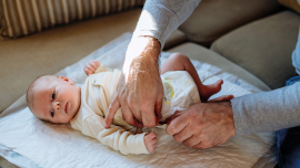 Mature father changing diaper his newborn bab. CREDIT -Istock-1486496053