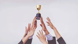 Hand holding trophy with others reaching for it. credit_istock-2165195635.