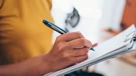 woman hand writing on clipboard with a pen. Credit_iStock-1434437996
