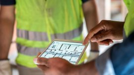 close up shot of electronic tablet being held by man in hi-vis jacket 