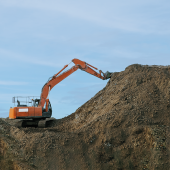Orange excavator moving soil on site.CREDIT_iStock-1280069901