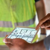 close up shot of electronic tablet being held by man in hi-vis jacket 